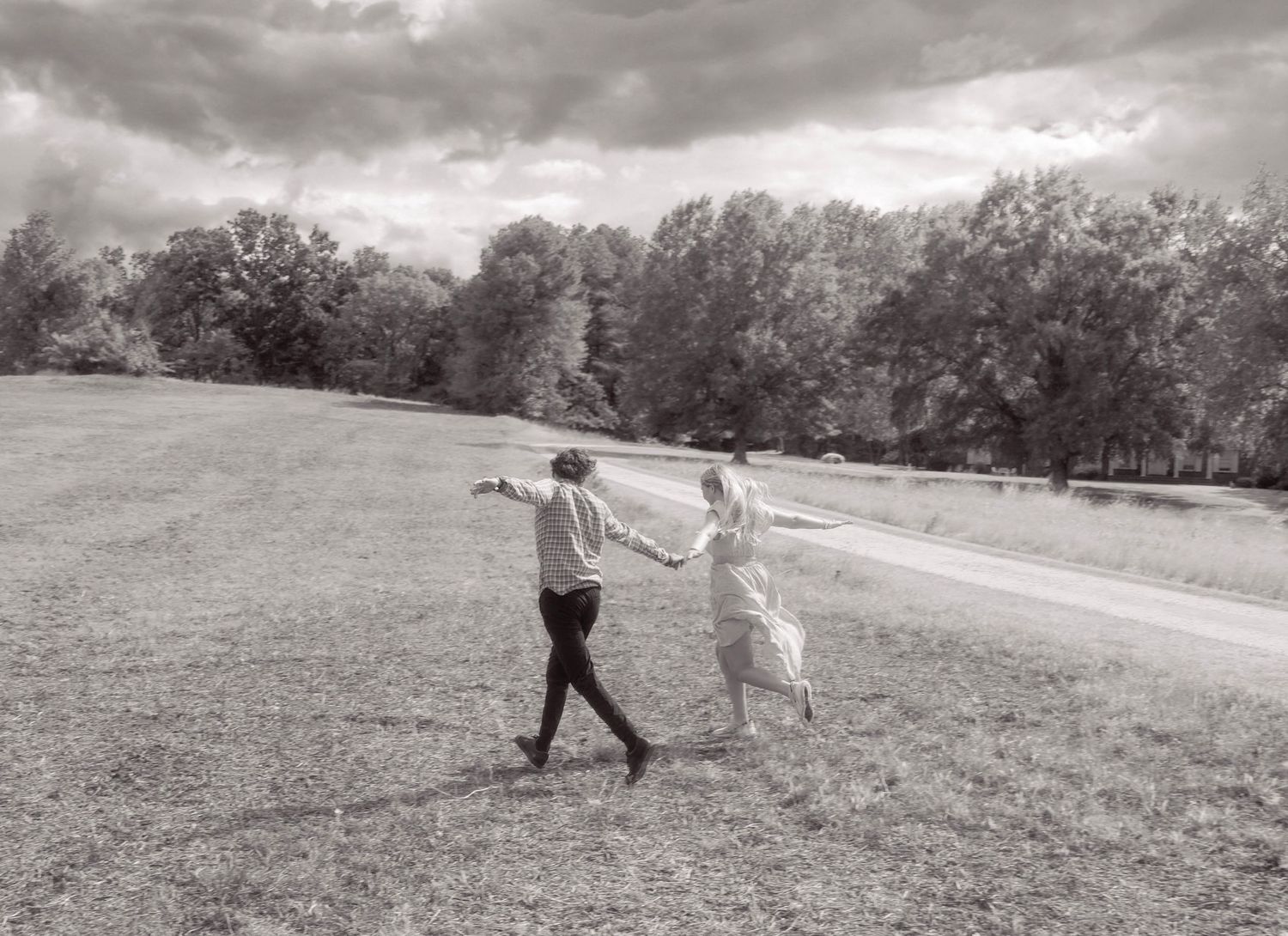 Black and white photo of couple dancing together in an open field.