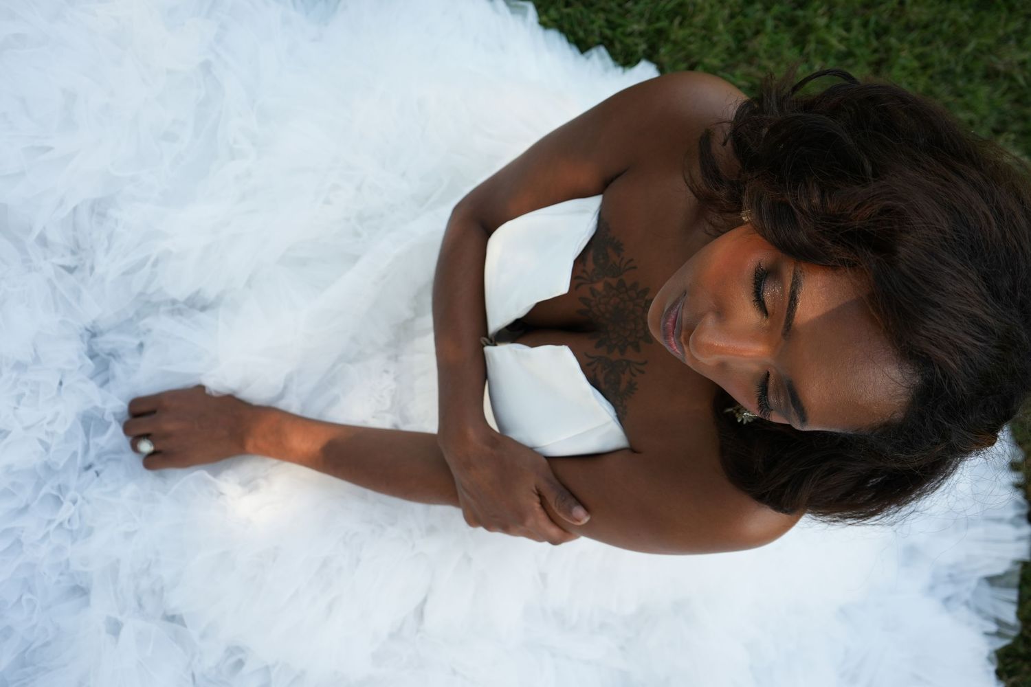 A bride in a white dress lies gracefully on snow-covered ground during a winter wedding photoshoot.