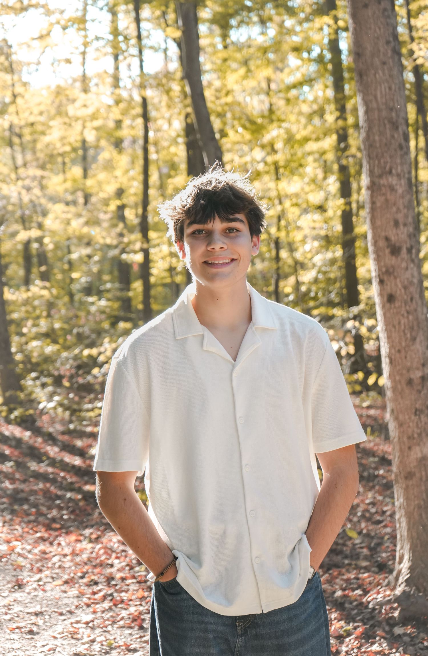 Three connected photos show someone in a white shirt and dark pants standing among autumn trees in a forest setting.