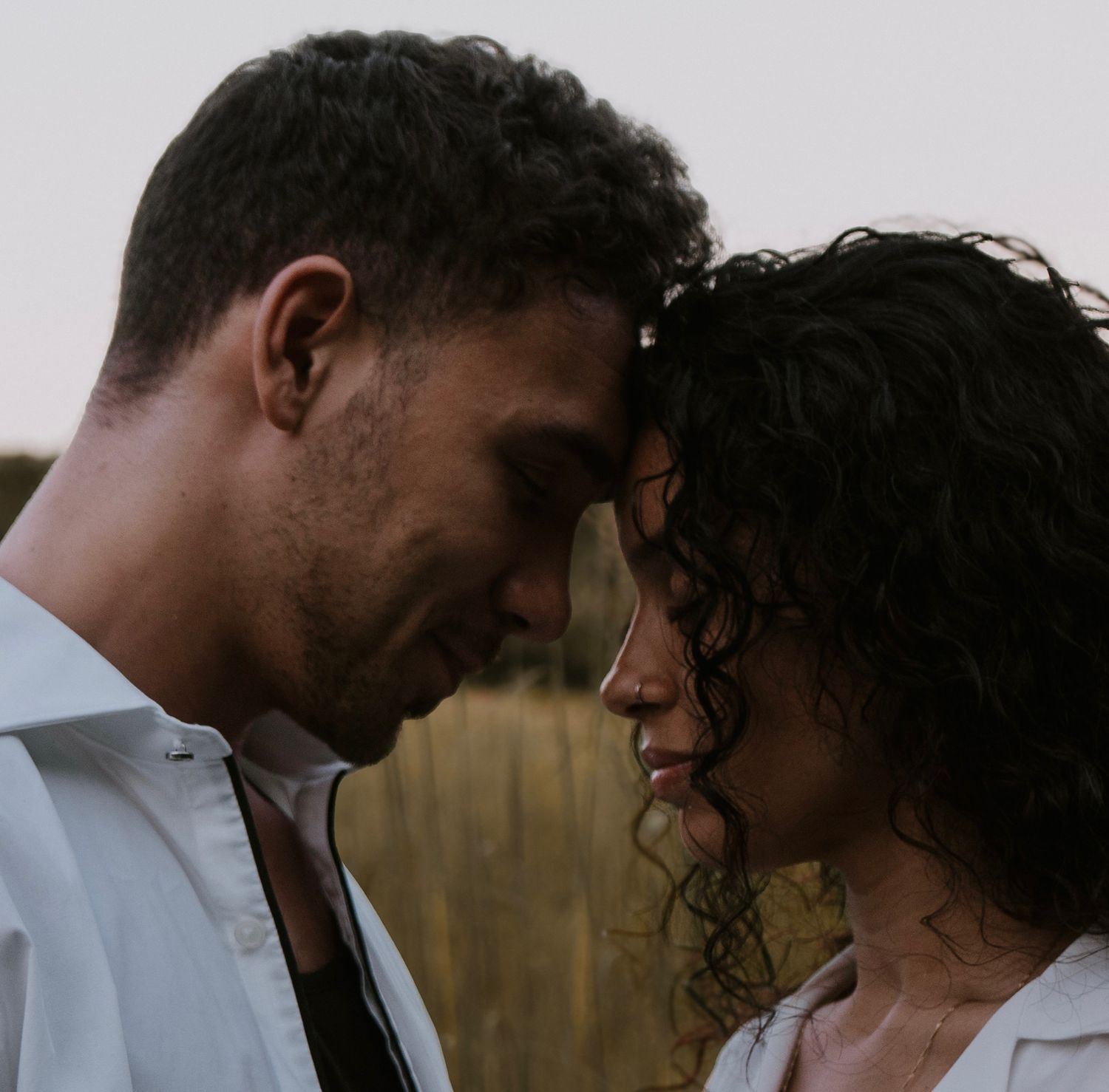 A couple shares an intimate moment together in a scenic outdoor setting at dusk.