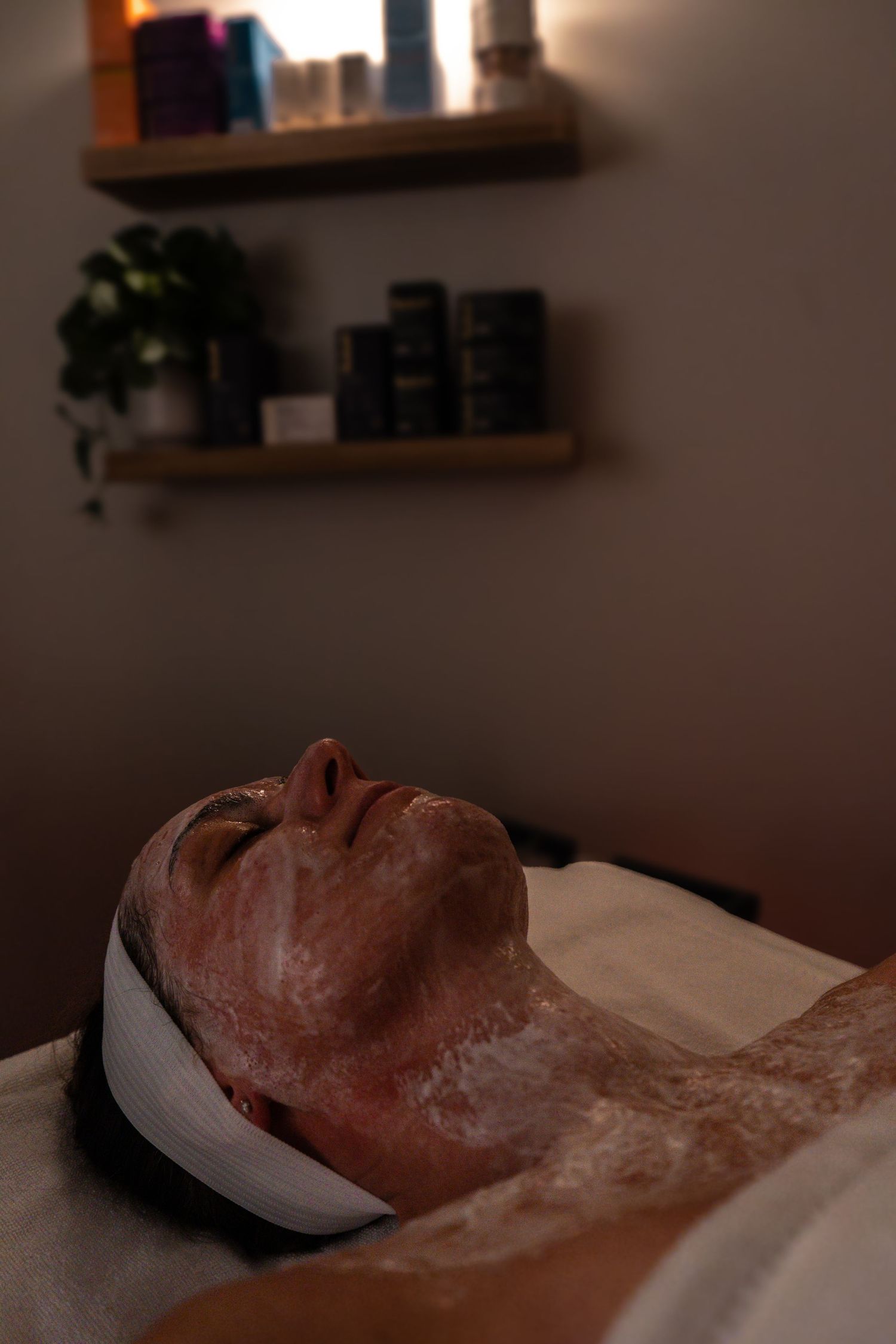Person receiving a spa facial treatment with a clay or mud mask while lying on a treatment table.