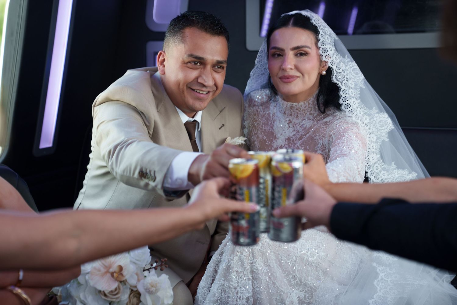 Bride and groom in wedding attire smiling and toasting with shot glasses at their wedding celebration.