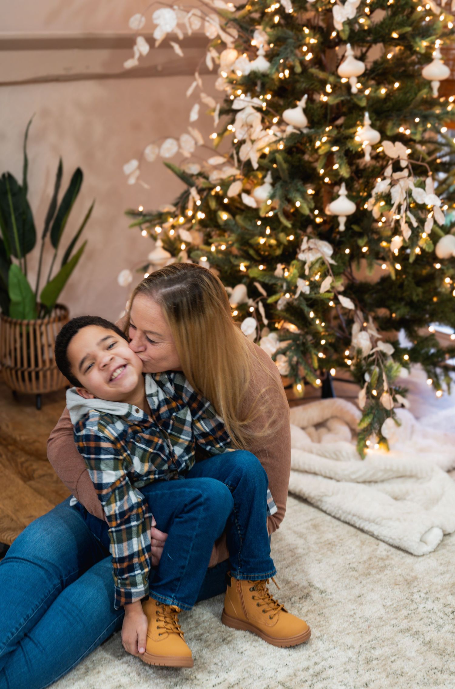 A festive holiday photoshoot with a decorated Christmas tree and cozy white rug setting.