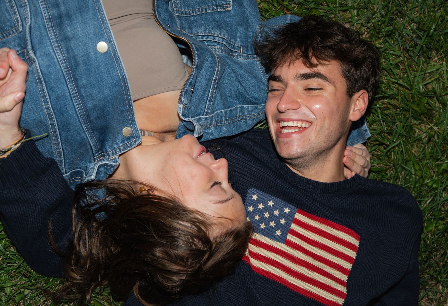 A couple shares a romantic moment outdoors with an American flag visible in the frame.