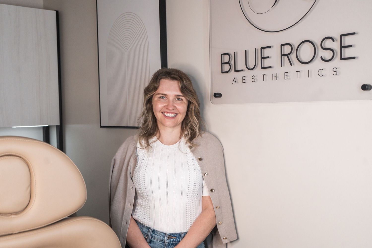 A medical aesthetic office interior with a beige treatment chair and a 'Blue Rose Aesthetics' sign on the wall.
