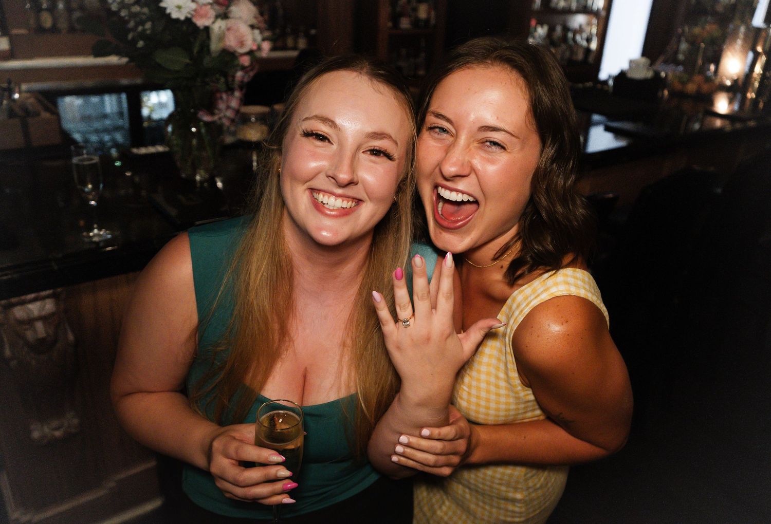 Two friends share laughter and smiles while enjoying a night out at a dimly lit venue.