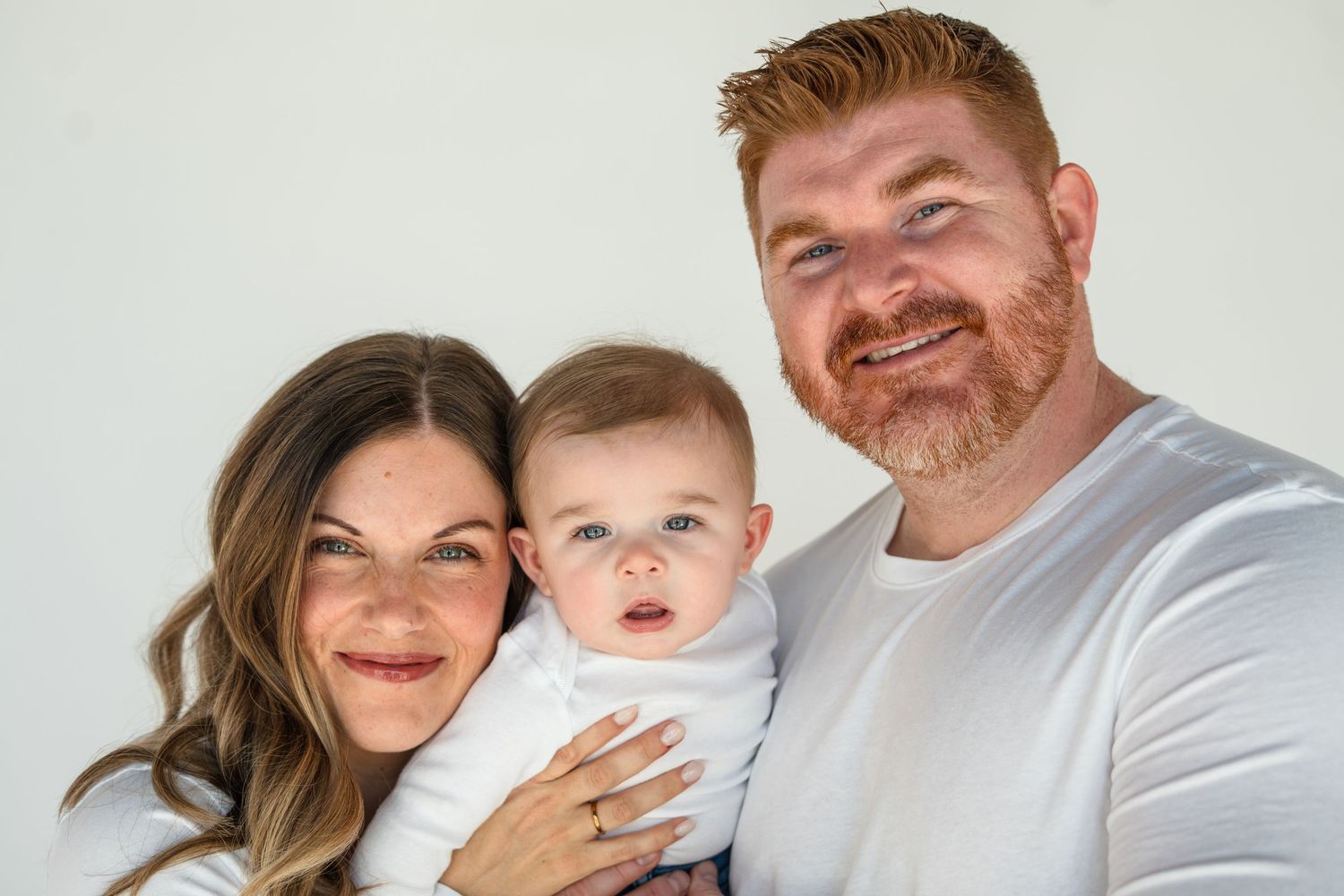 A family in white shirts poses together for a series of casual portrait photographs.