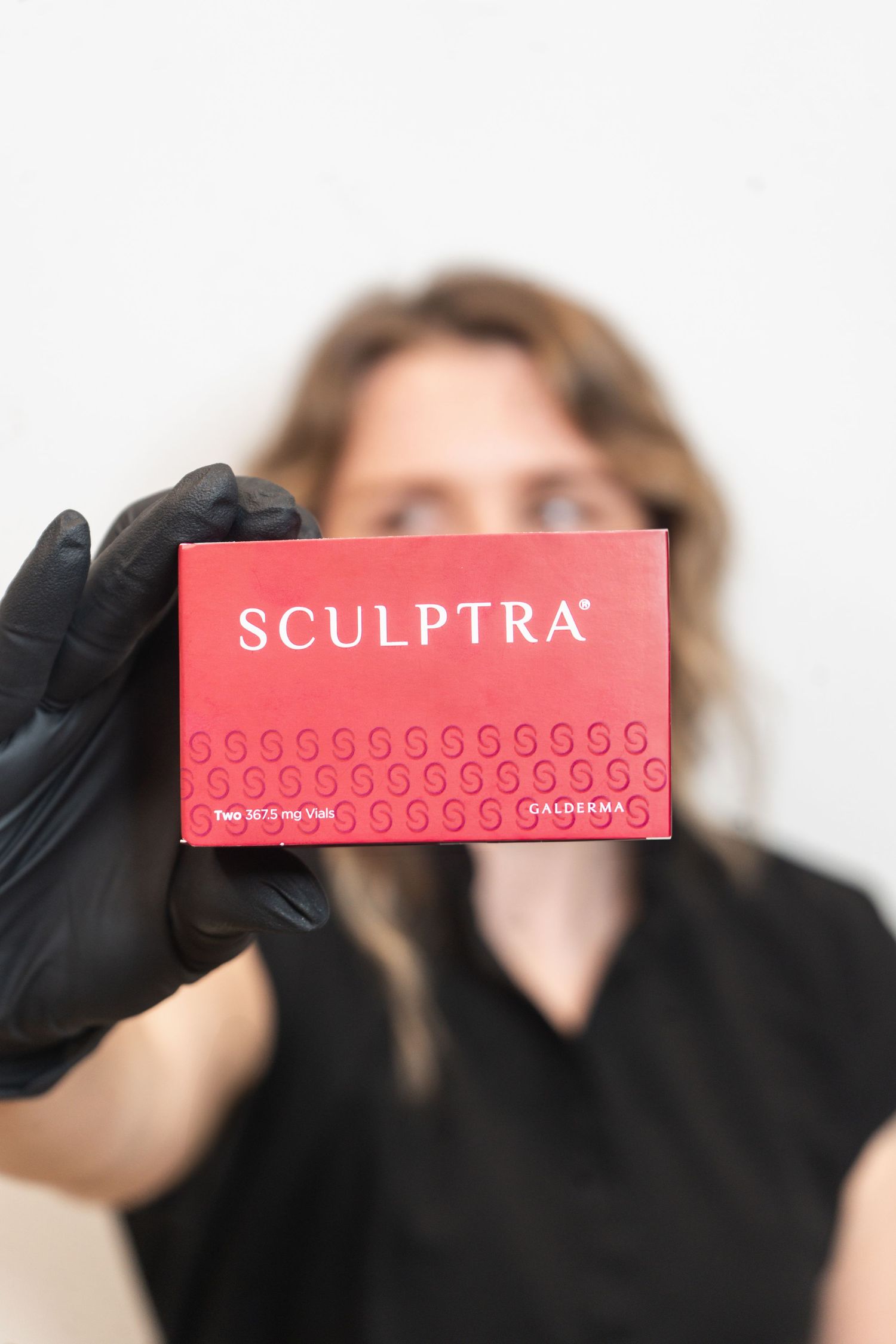 Medical professional in black gloves demonstrating the use of Sculptra injectable treatment product.