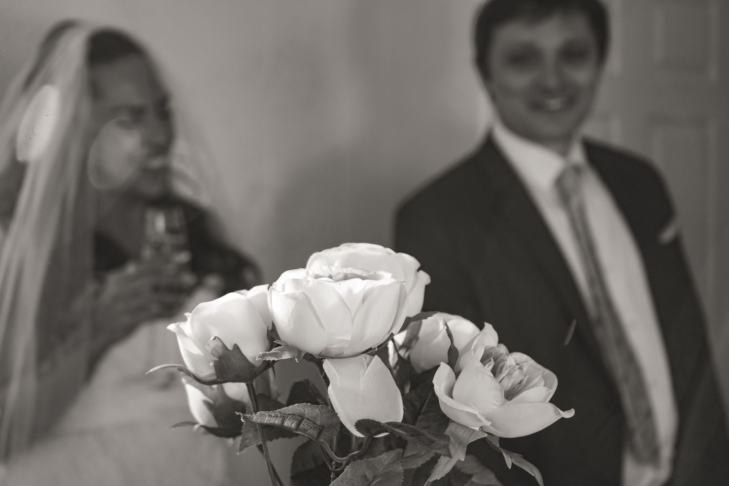 Black and white wedding photo with roses in foreground.
