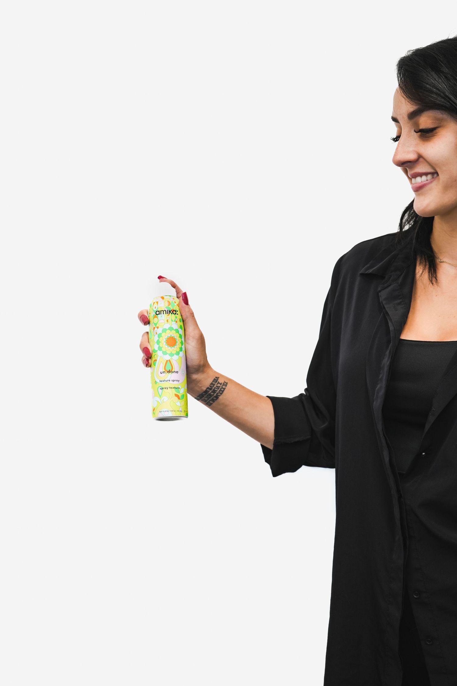 Woman in black blazer holding and displaying a canned beverage product against white background.