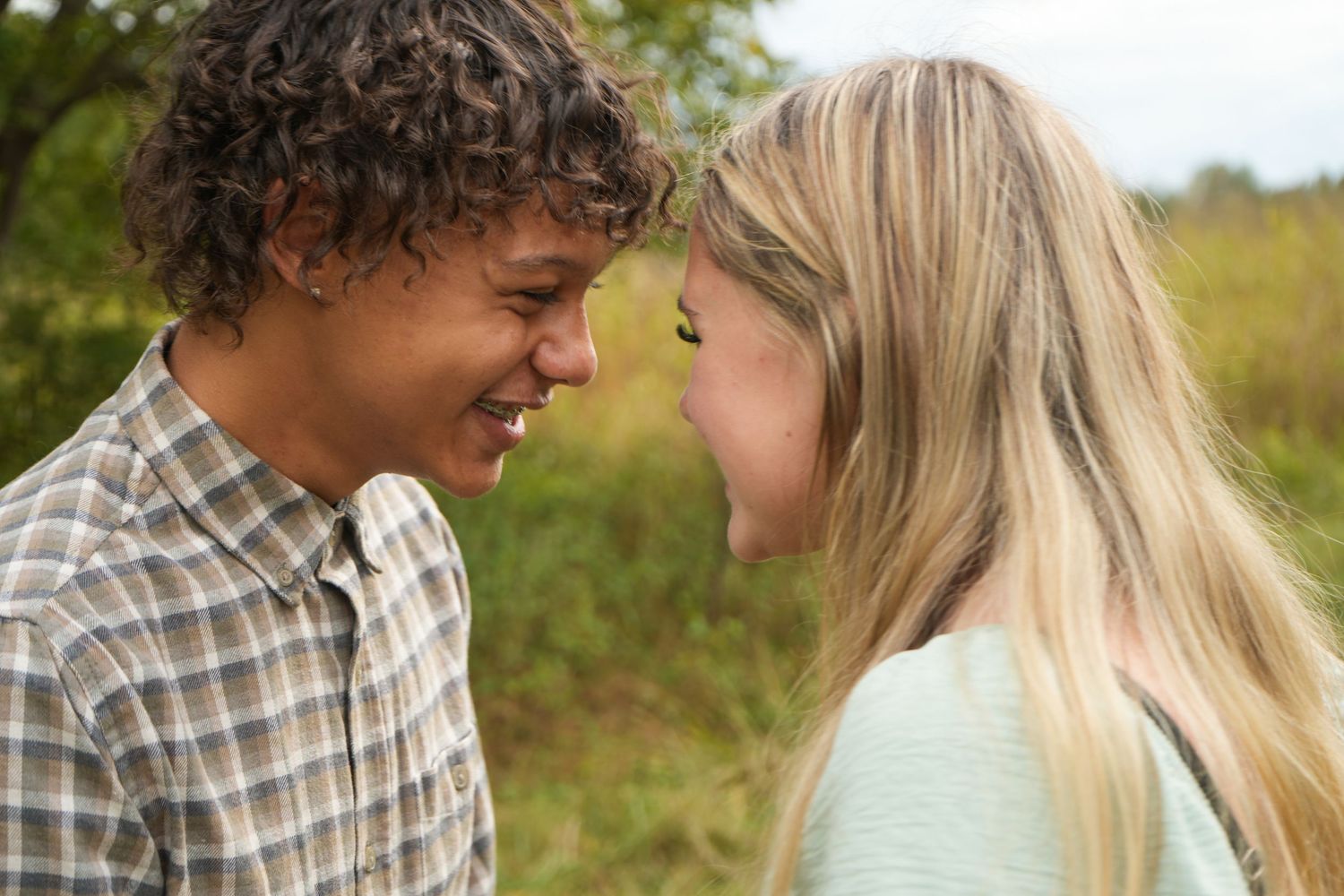 A series of candid moments captured between a couple in a sunlit meadow.