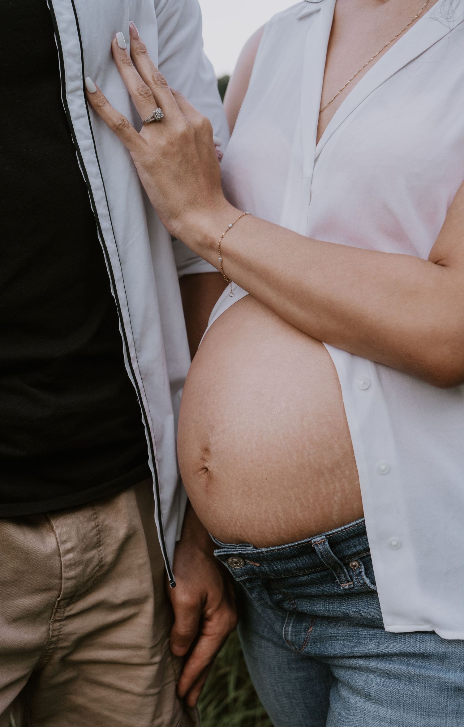 Close-up progression photos of a growing pregnant belly shown with jeans and white shirt over multiple stages of pregnancy.