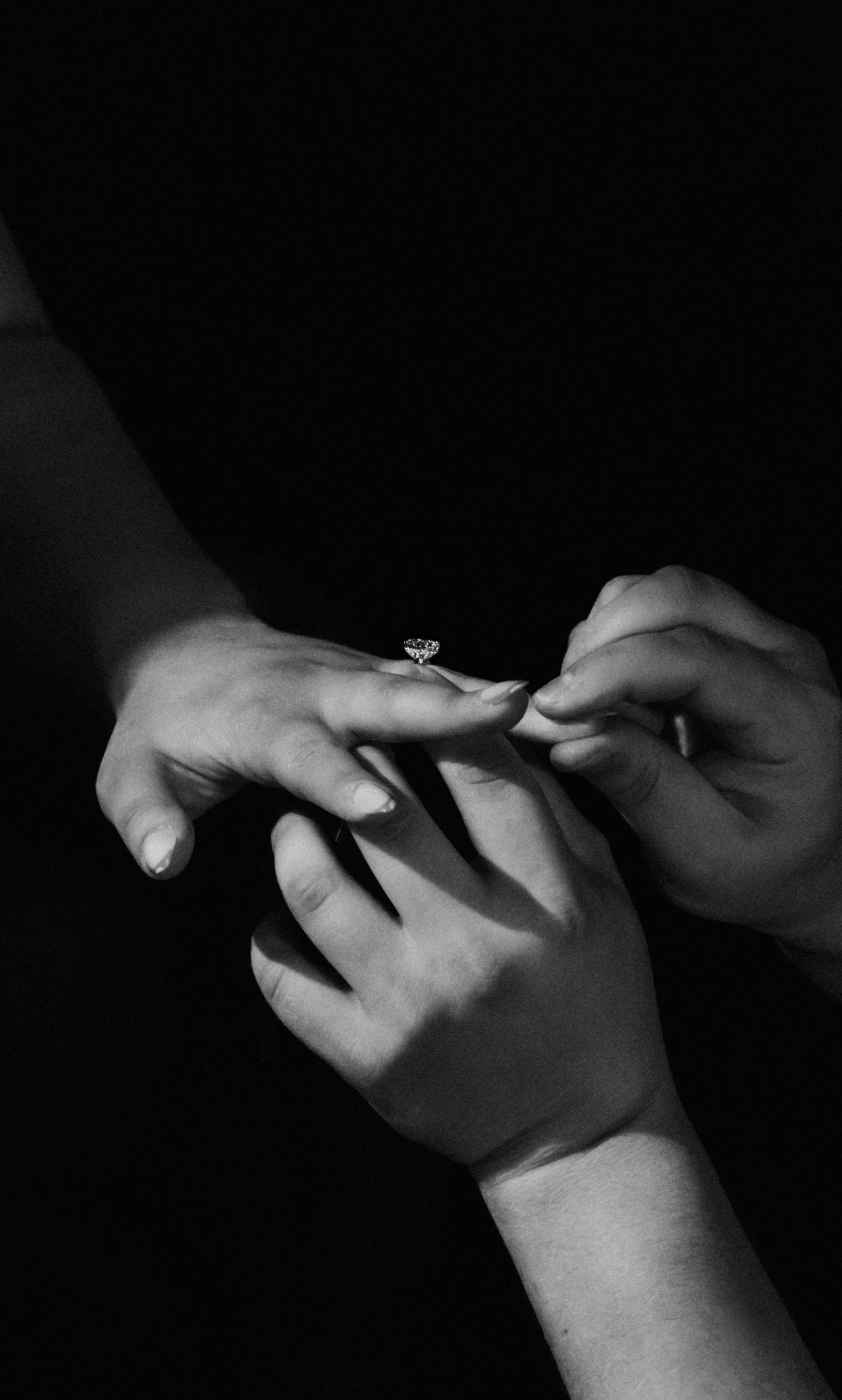 A series of black and white photographs showing hands exchanging a ring in dramatic lighting.