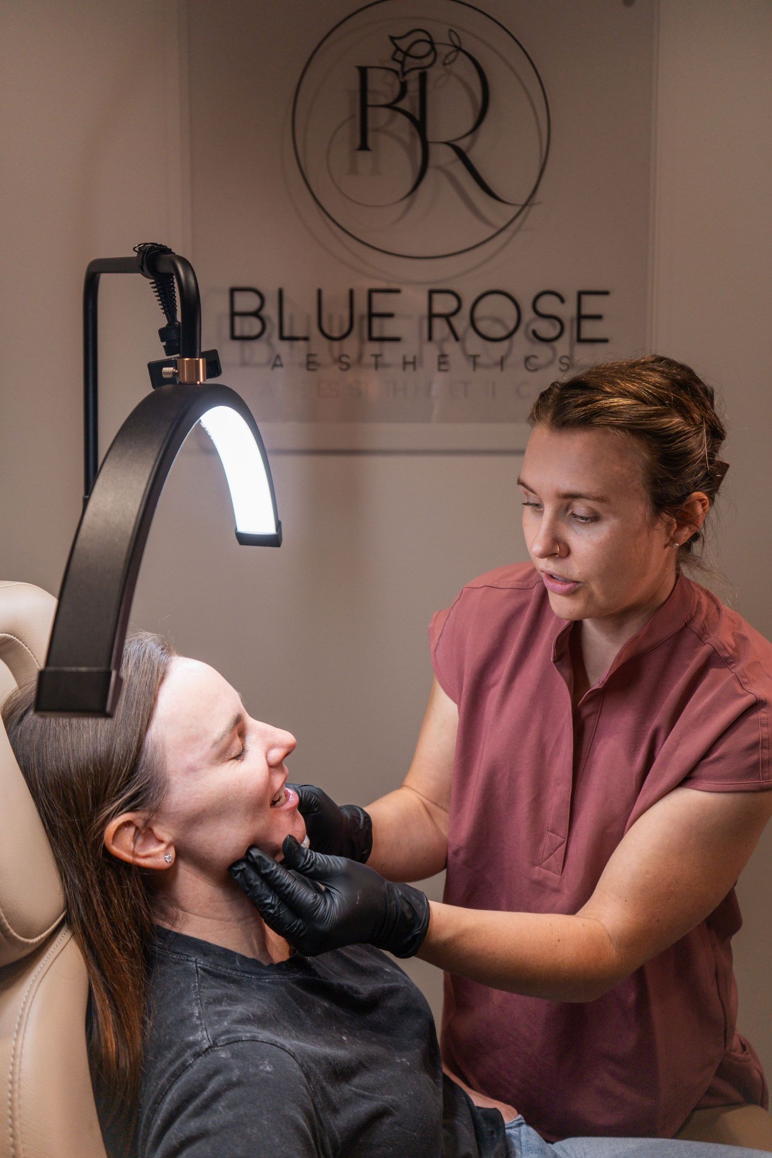 A medical professional performs a cosmetic treatment procedure in a spa setting with Blue Rose branding visible.