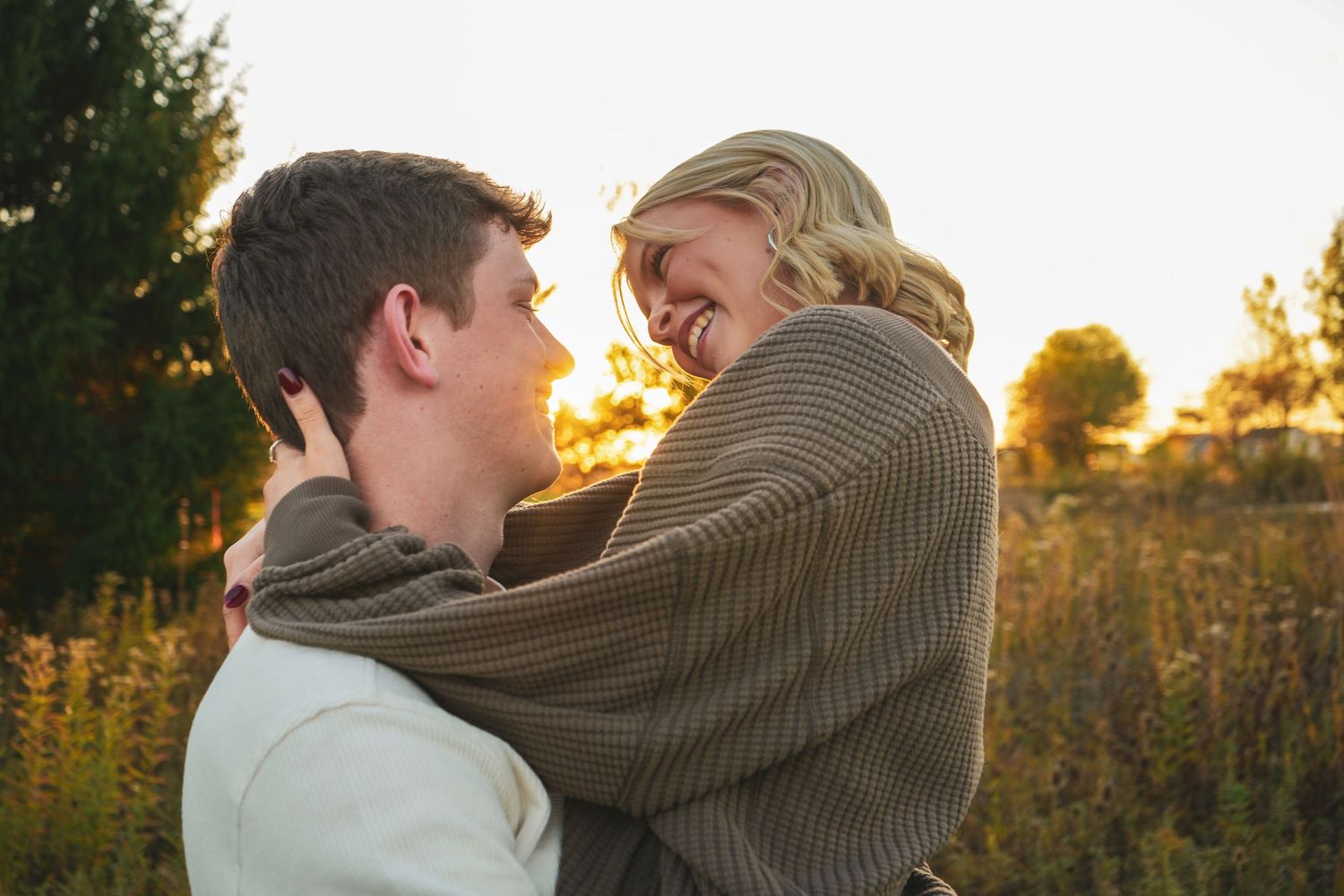 Romantic couple embracing in a golden sunset field.