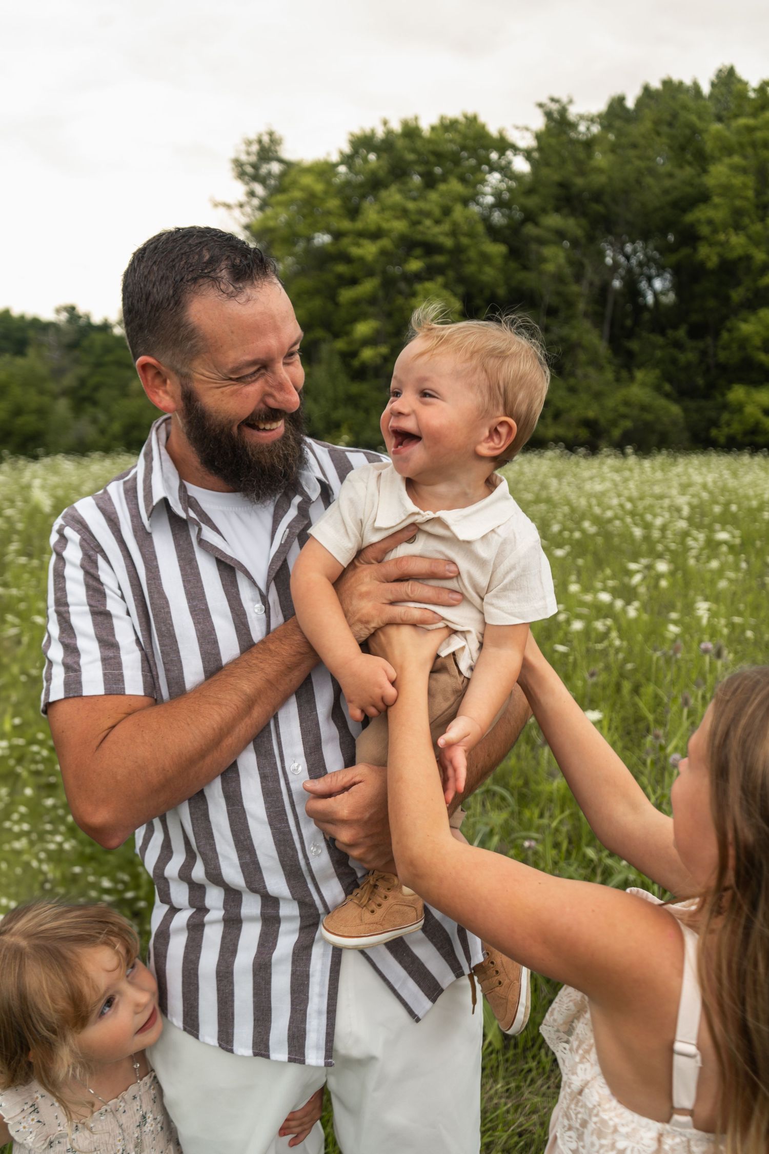 A family shares joyful moments together in a blooming summer meadow filled with white wildflowers.