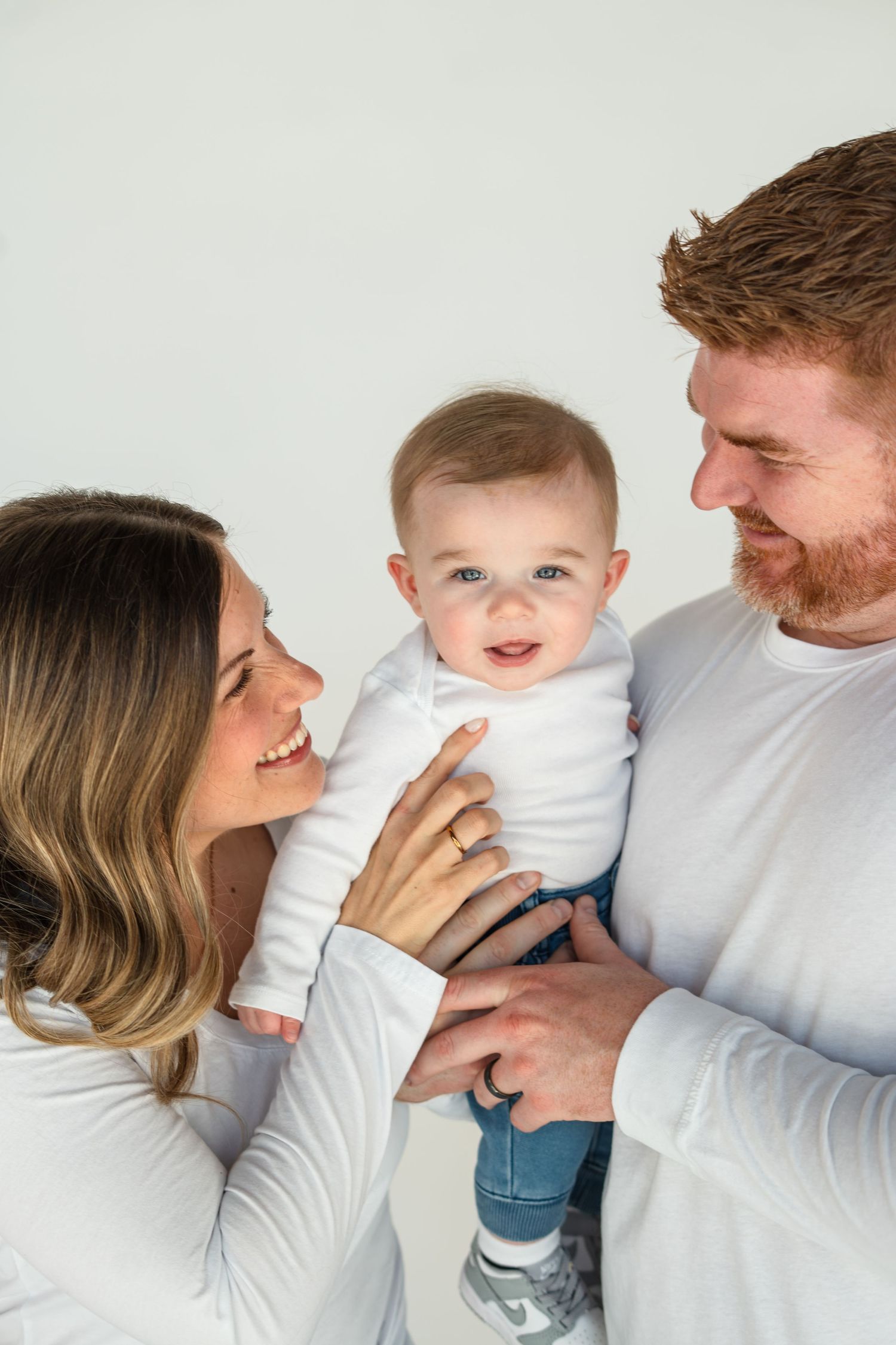 A series of four candid family photos showing tender moments between parents and baby against a white background.