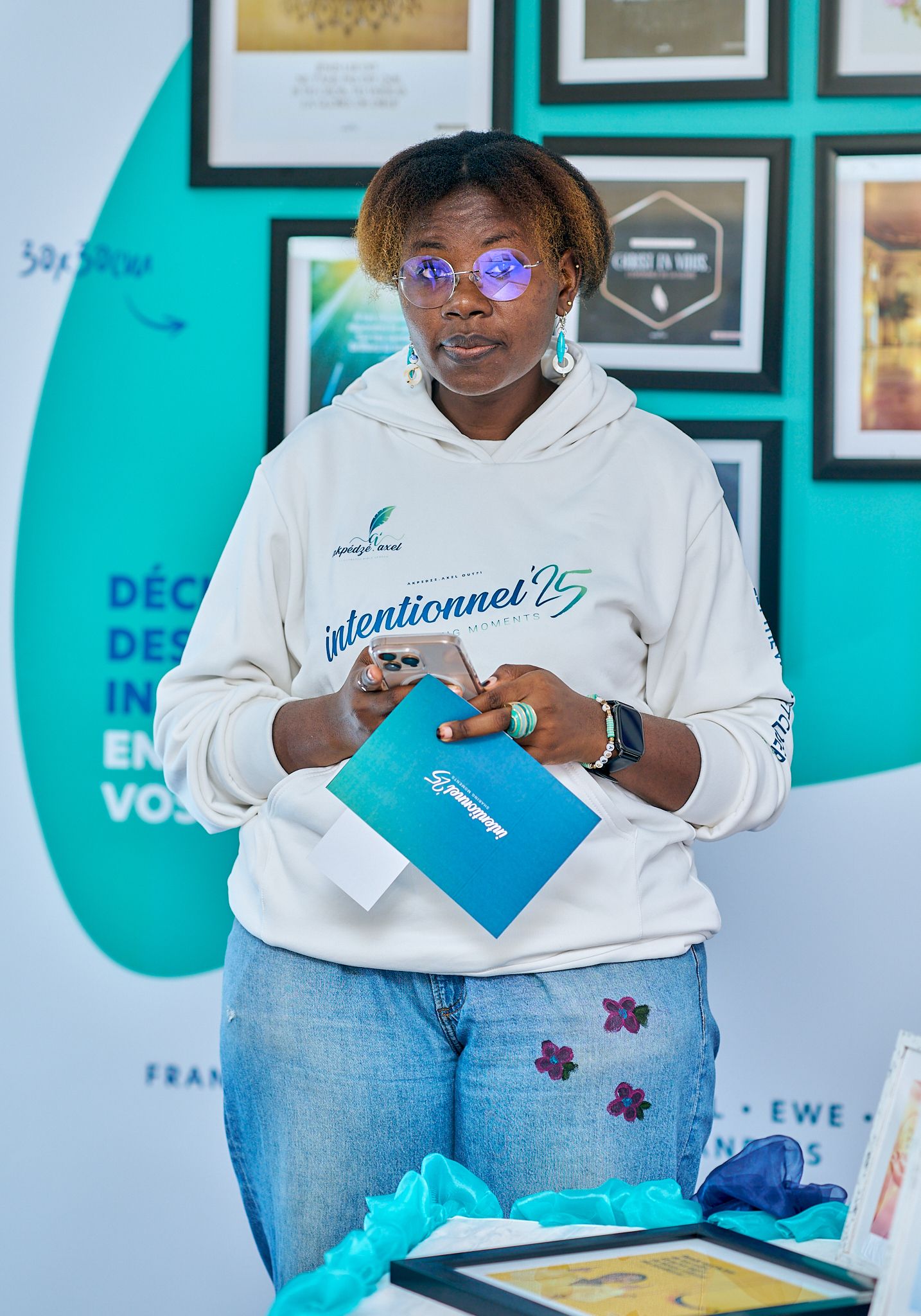 Person wearing white sweatshirt and jeans sitting in office with turquoise walls and framed artwork at sharing moment called intentionnel