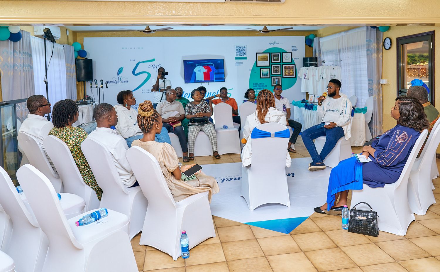 Row of people seated in white chairs at an indoor event at sharing moment called intentionnel