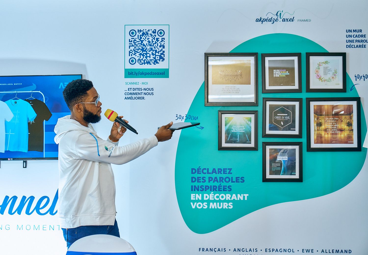 Speaker presenting in front of wall display with QR code and framed artwork.