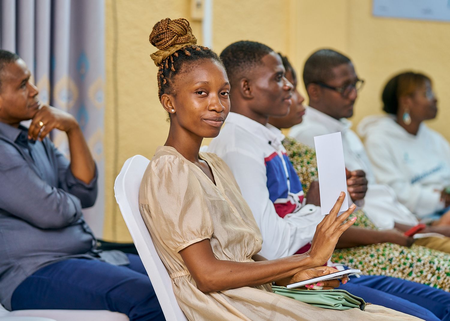 Audience members seated and watching a presentation in a yellow-walled room at sharing moment called intentionnel