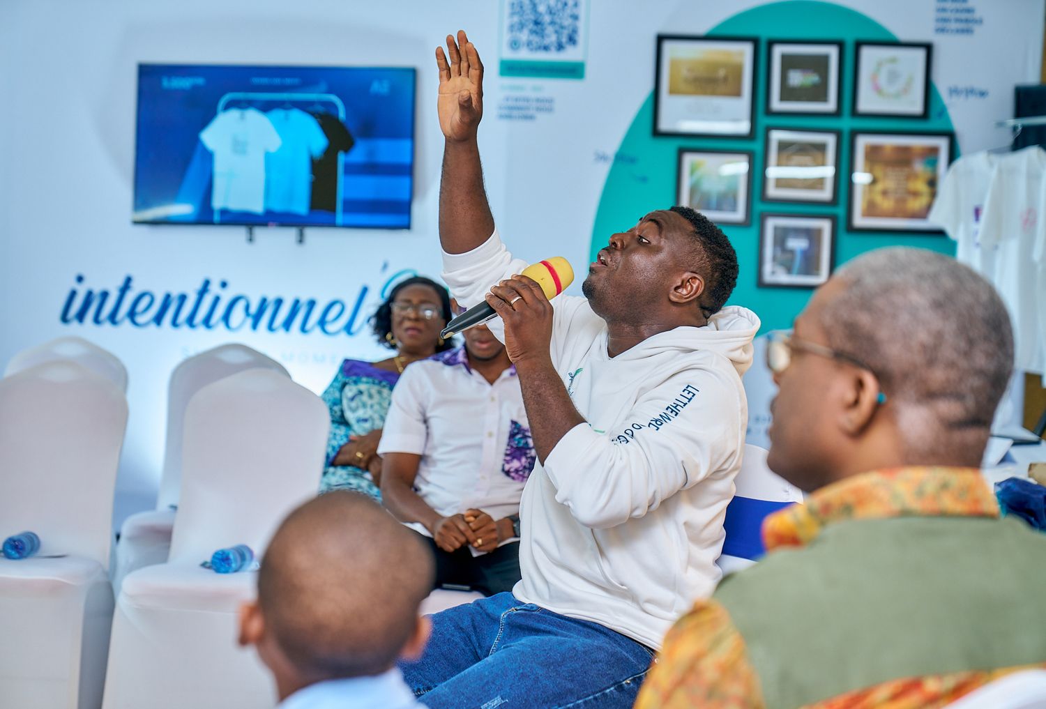 Participants engaging during praise and worship time at sharing moment called intentionnel with white chairs and blue accents.