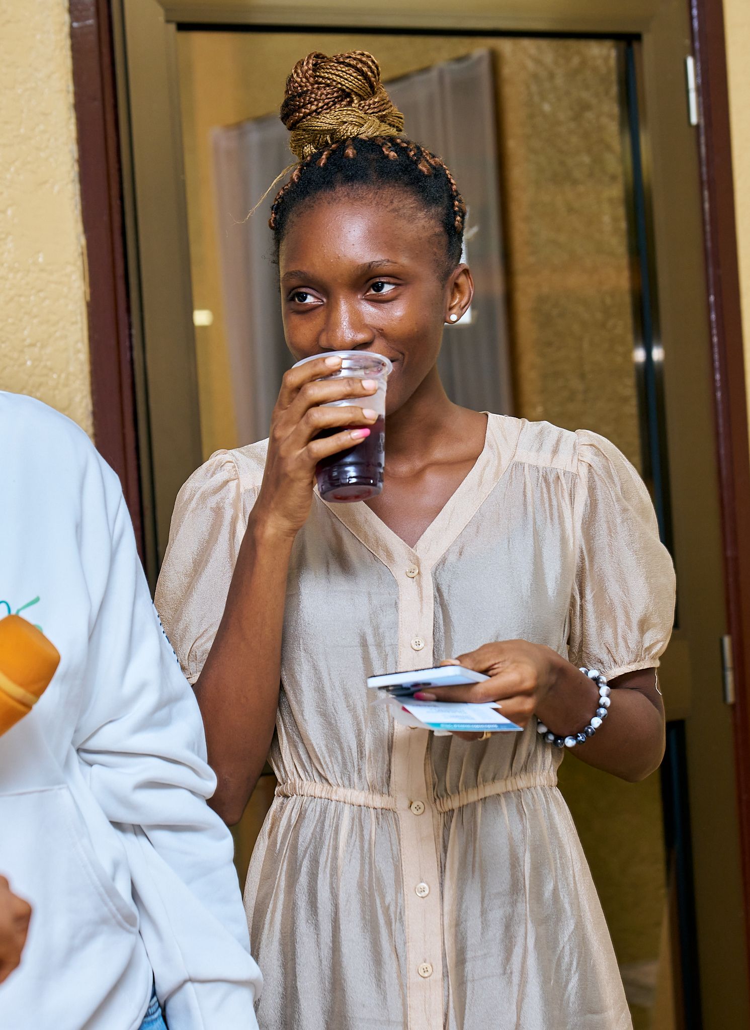 Person in beige dress enjoying refreshments at social gathering called intentionnel, a sharing moment