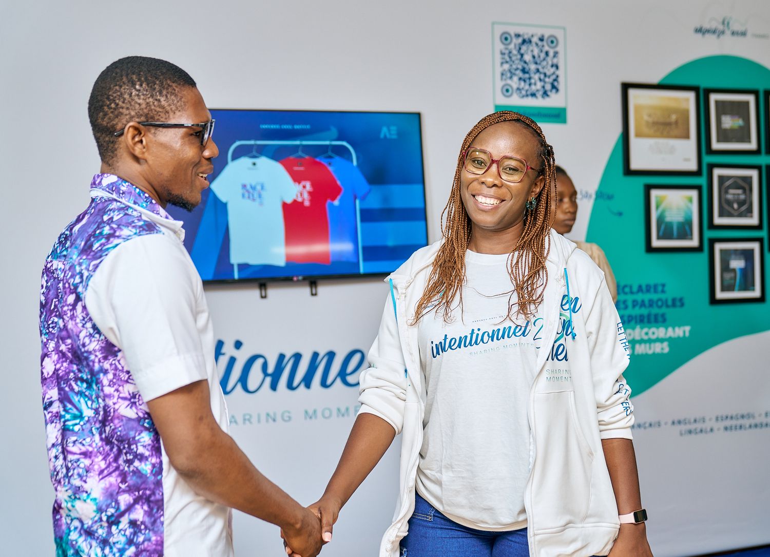 Two people having conversation in front of branded wall display with framed artwork during sharing moment called intentionnel