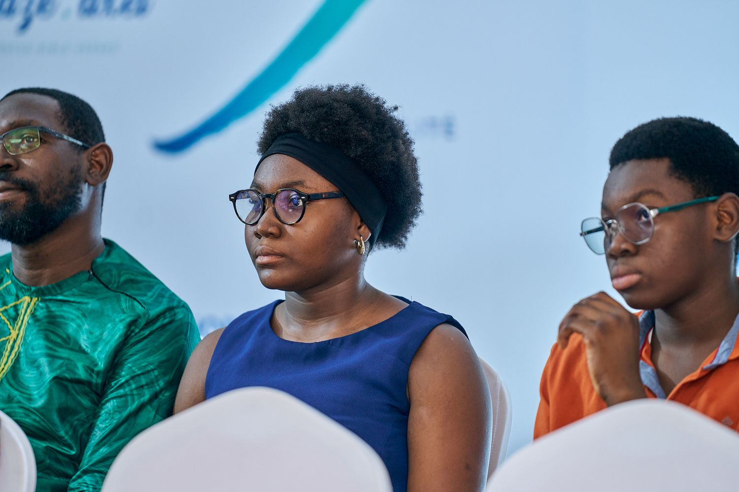 People seated in a row at a professional event, a sharing moment called intentionnel wearing formal attire.