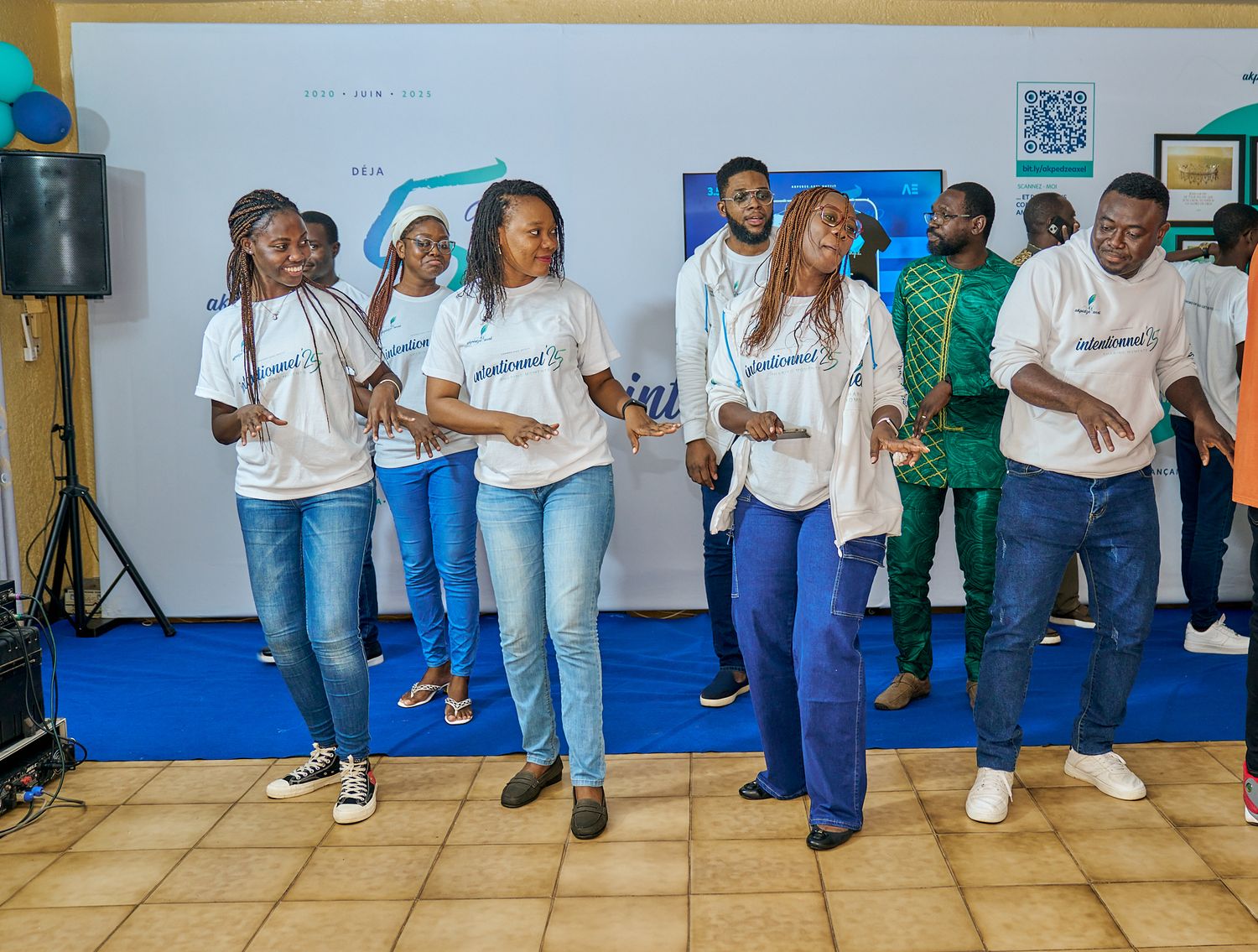 Group gathering in casual attire posing in front of blue wall with company branding at sharing moment called intentionnel