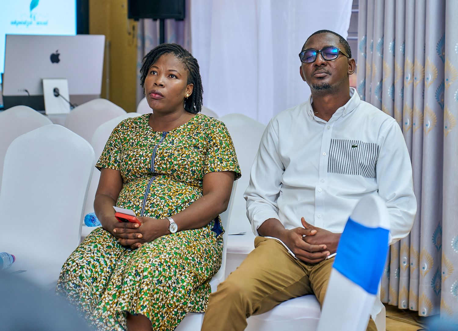 Two attendees seated in white chairs at indoor event venue called intentionnel, a sharing moment