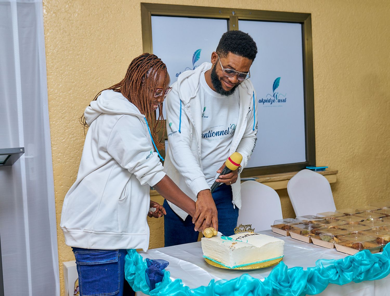 Two people cutting a celebration cake decorated with blue accents at sharing moment called intentionnel