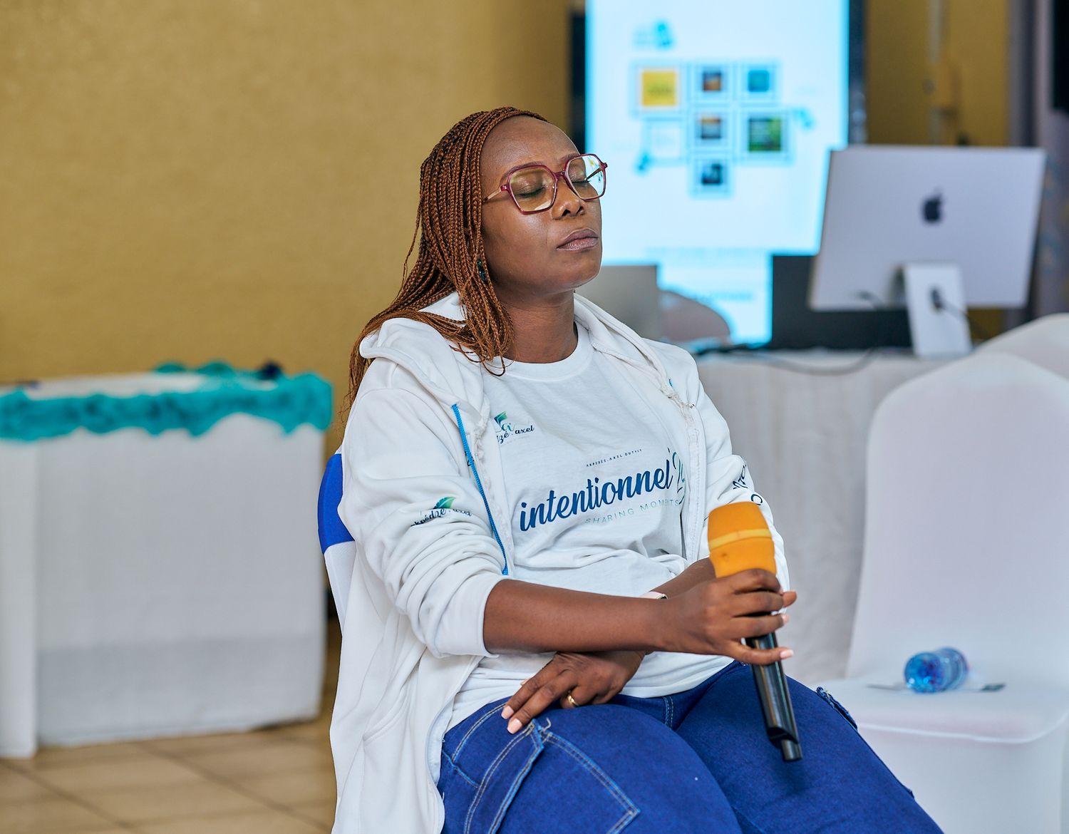 Person in white sweatshirt and blue pants holding orange drink during sharing moment called intentionnel