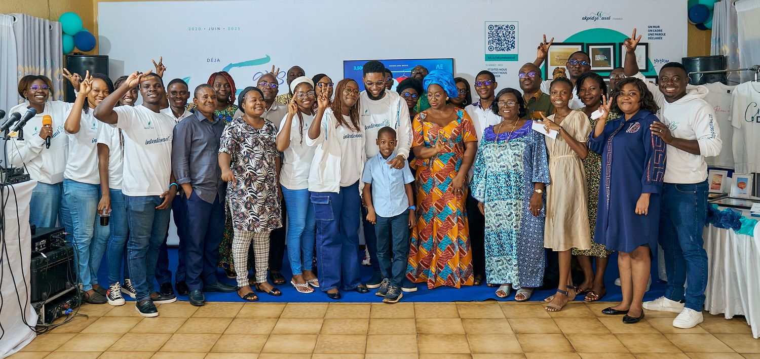 Large group photo of event participants standing together with turquoise balloon decorations during sharing moment called intentionnel