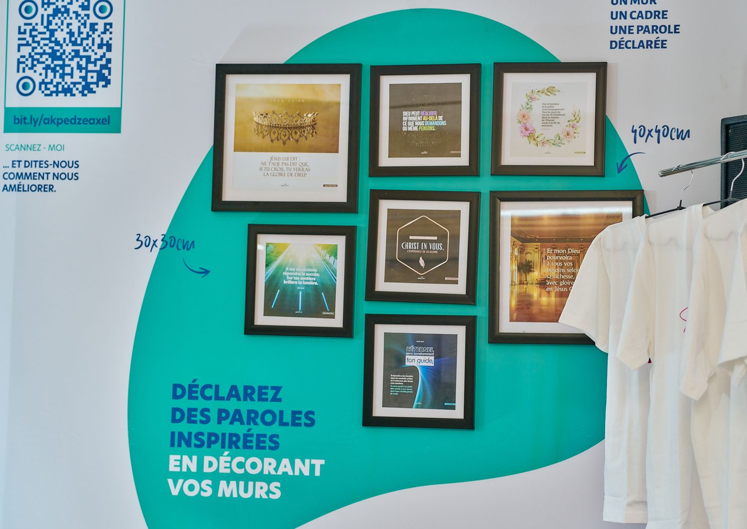 Gallery wall with framed artwork against a turquoise accent wall with white t-shirts visible.