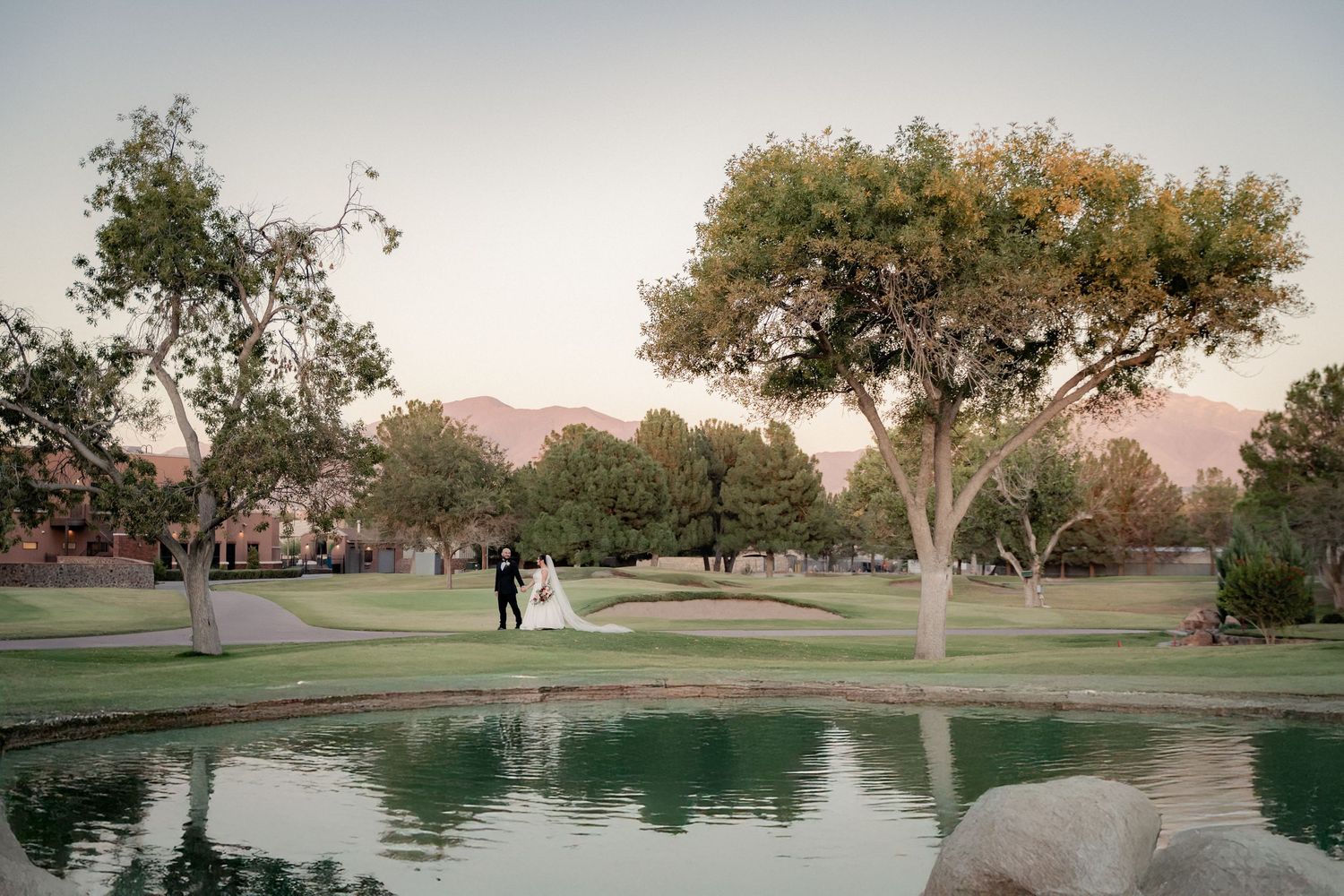 Scenic golf course wedding venue with pond reflection and mountain backdrop.