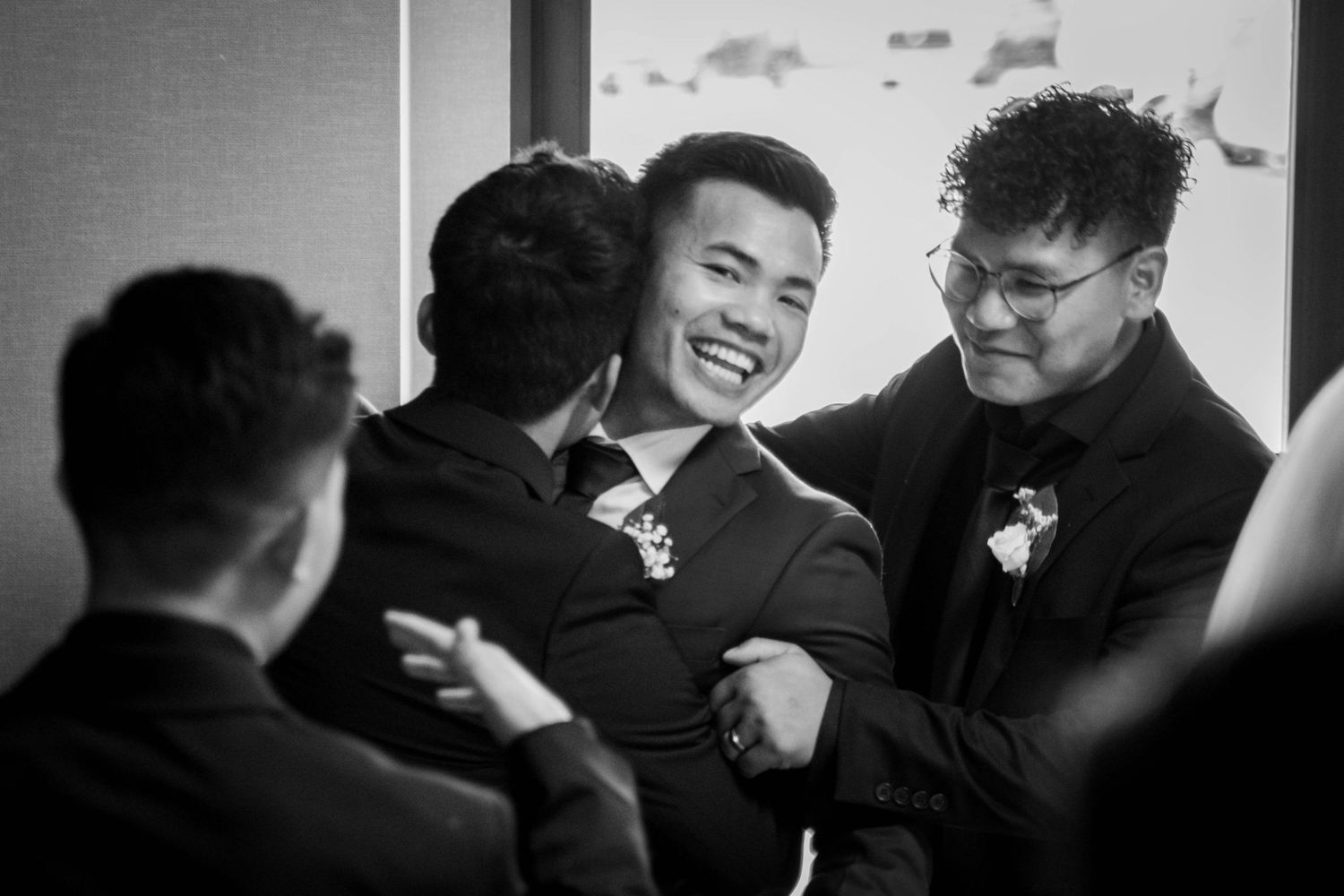 Candid black and white photo capturing joyful laughter among wedding guests.