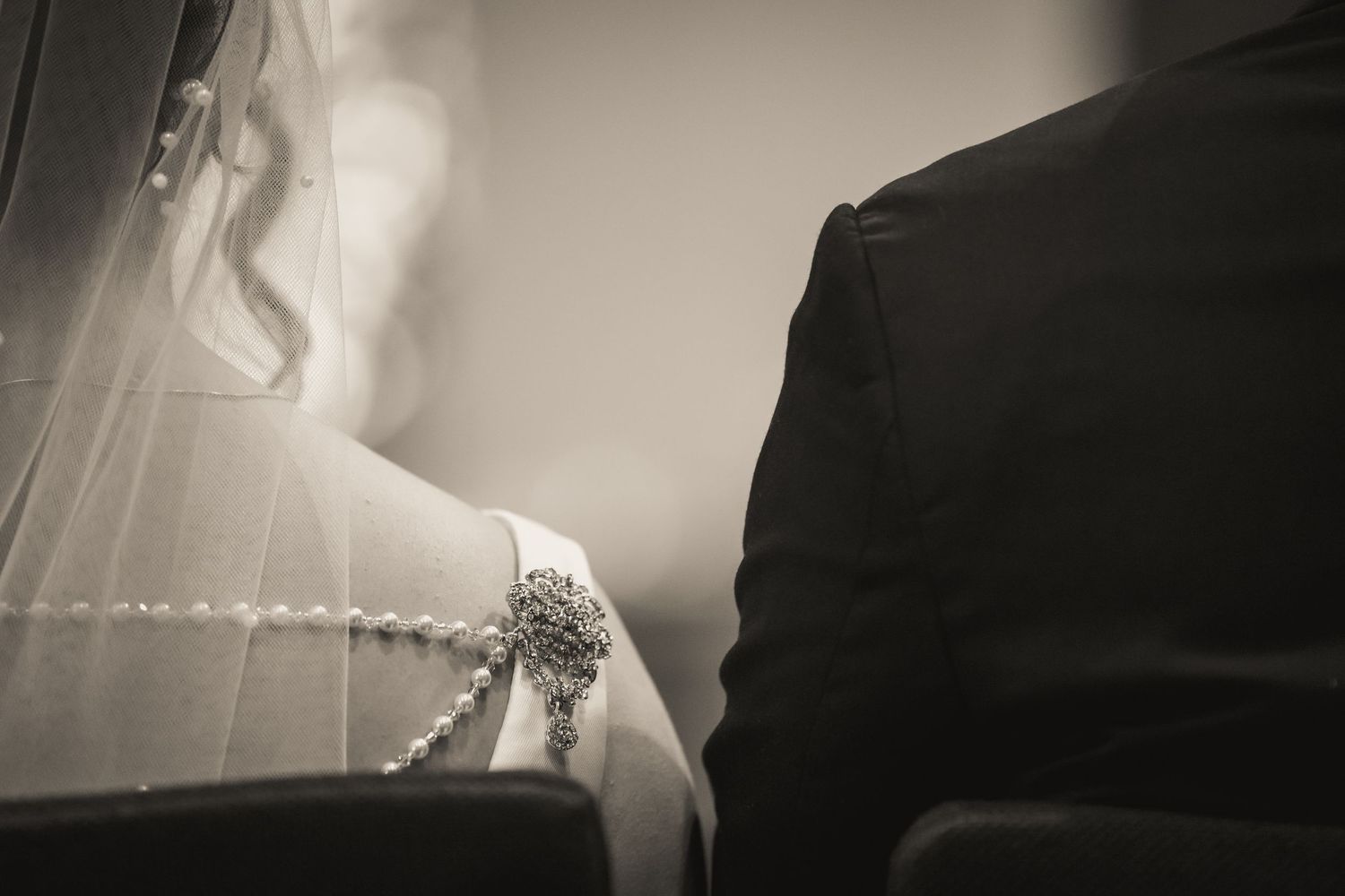 Detail shot of a bride's sparkly wedding shoe next to groom's black tuxedo.