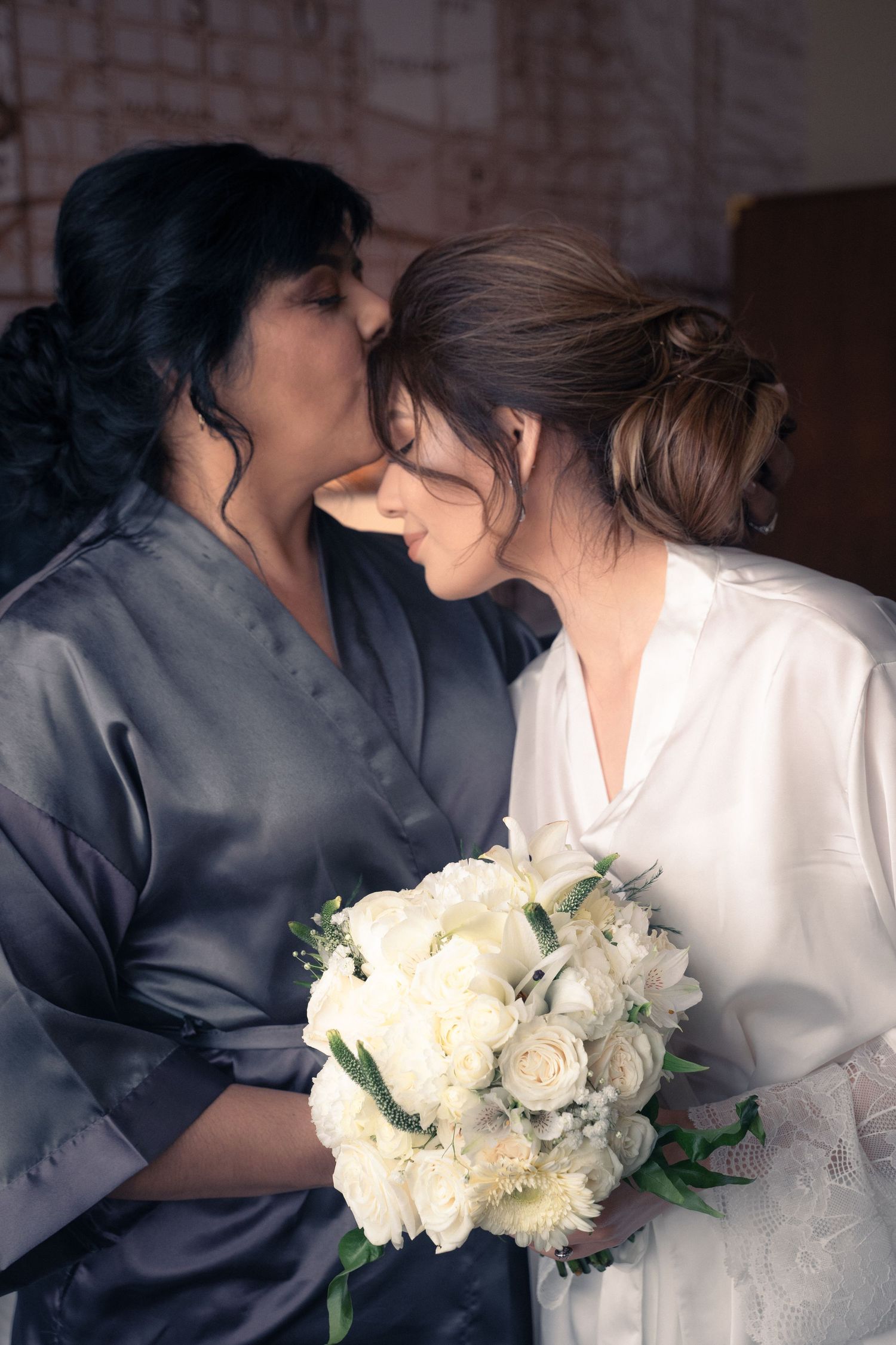 Two people in contrasting silk robes sharing an intimate moment with white flowers.