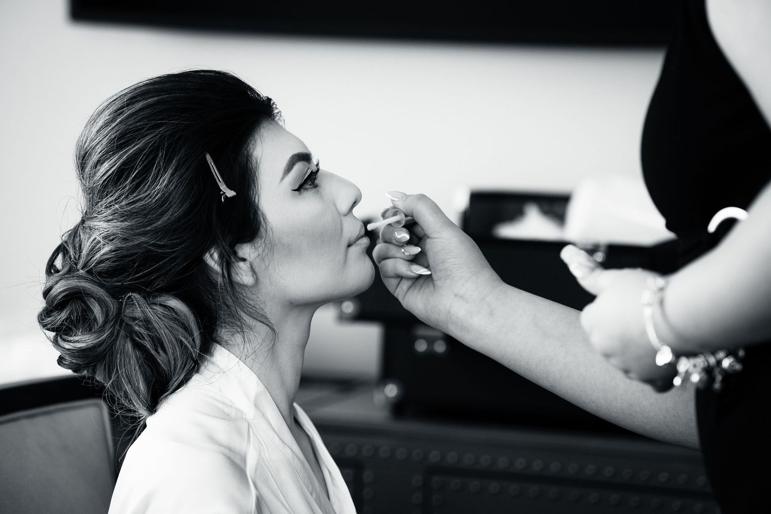 Black and white photo showing final wedding day makeup preparations.