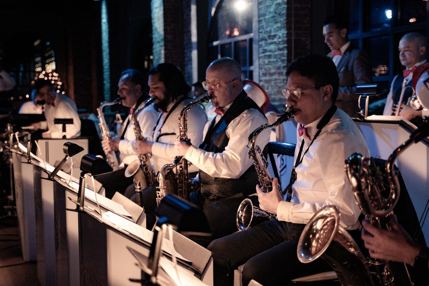 Musicians in tuxedos performing with brass instruments at a wedding reception.