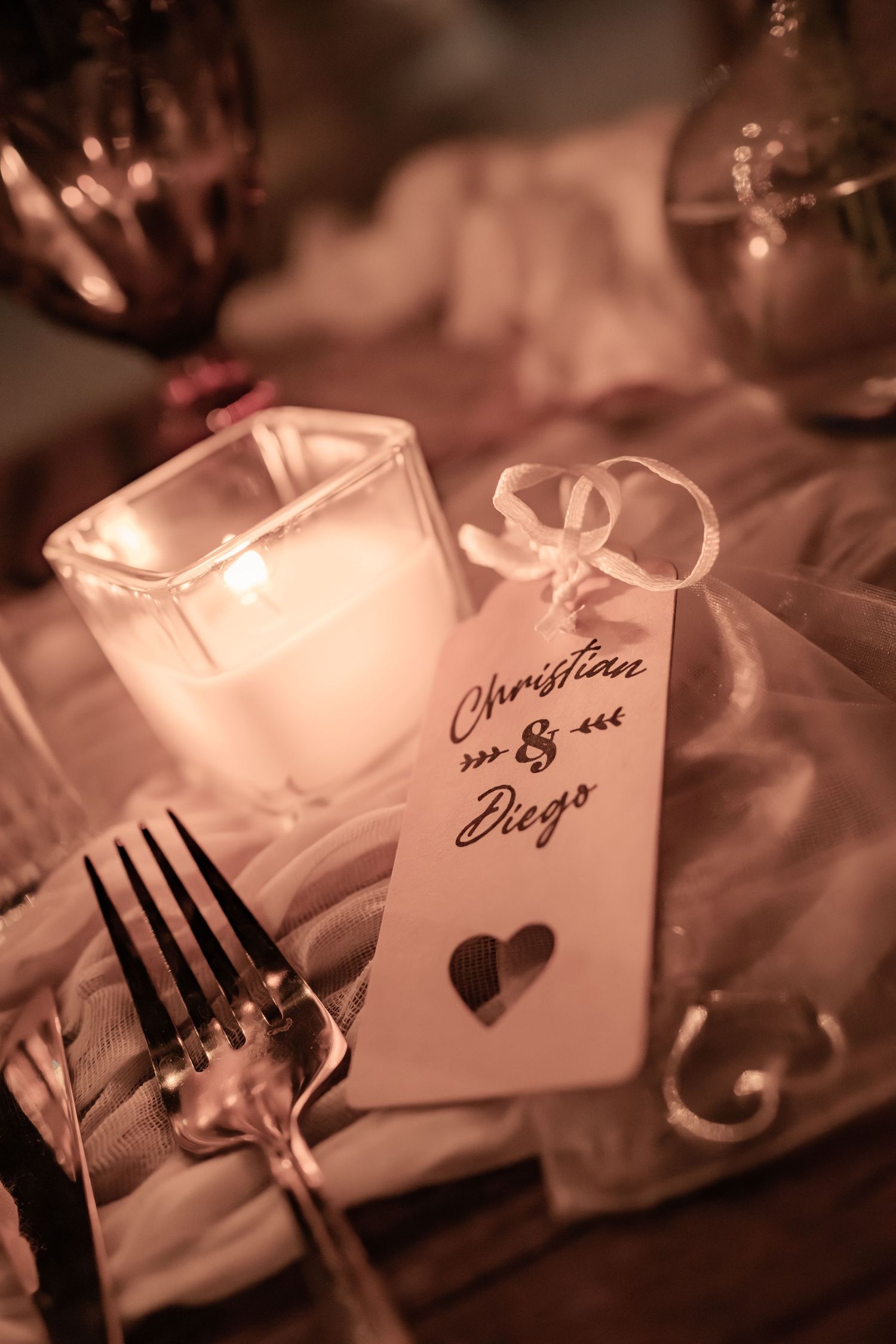 Romantic place setting with candlelight and wedding gift tag featuring a heart shape in soft sepia tones.
