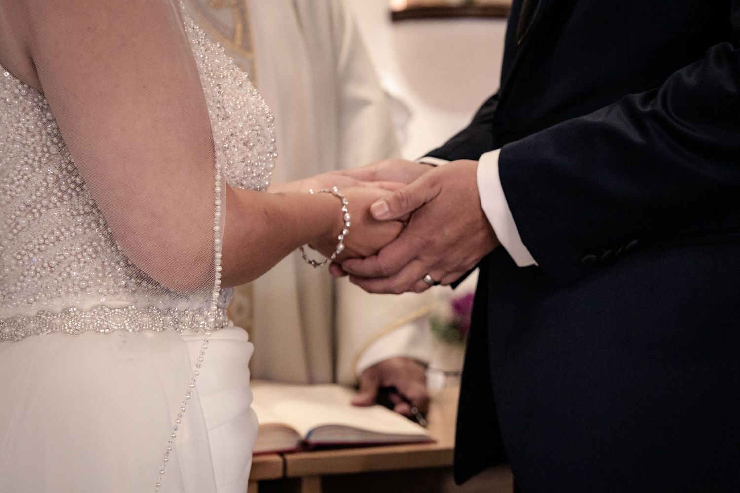 Close-up of hands exchanging rings during wedding ceremony at church altar.
