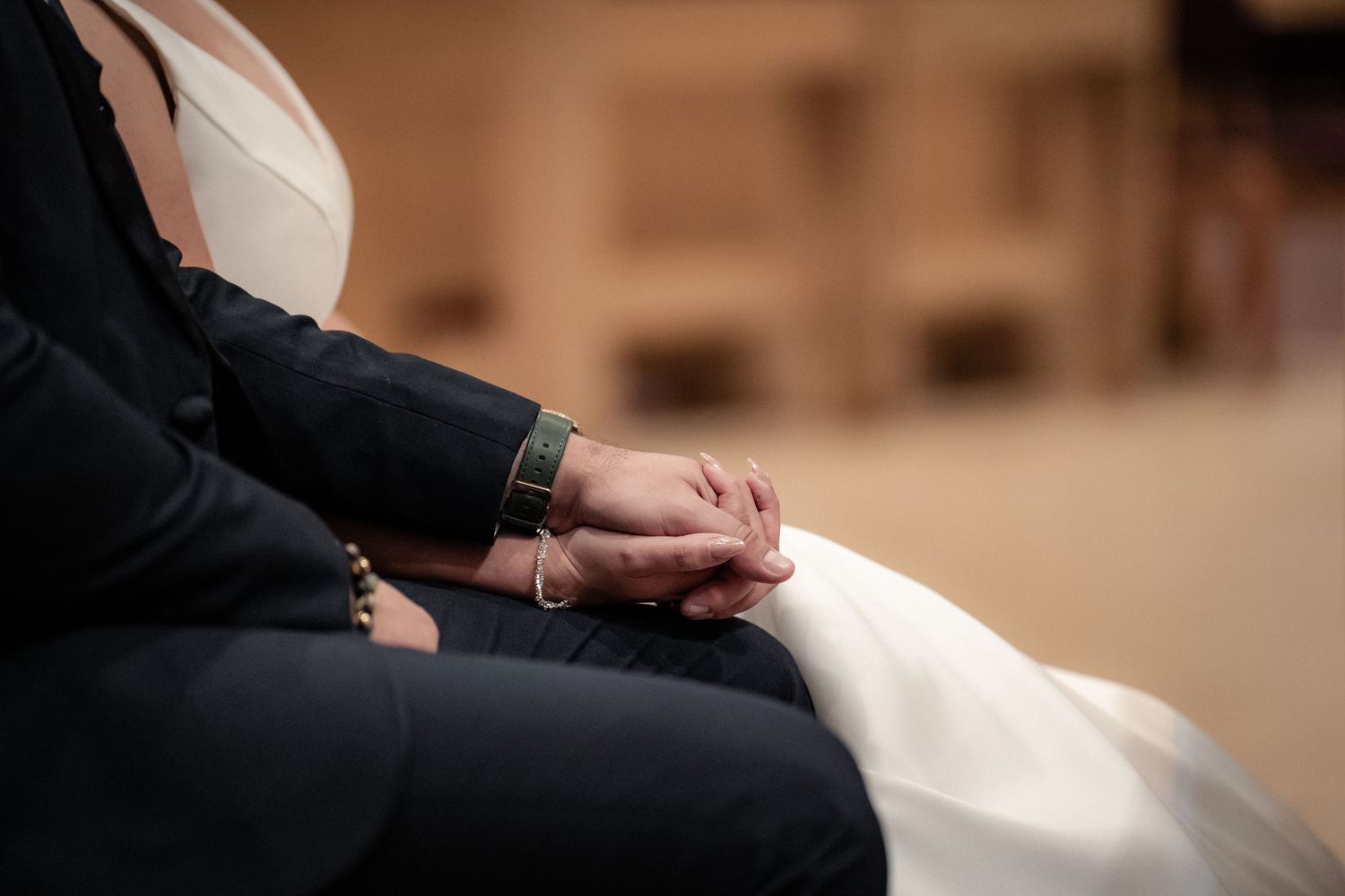 Close-up of clasped hands during an intimate wedding ceremony moment.