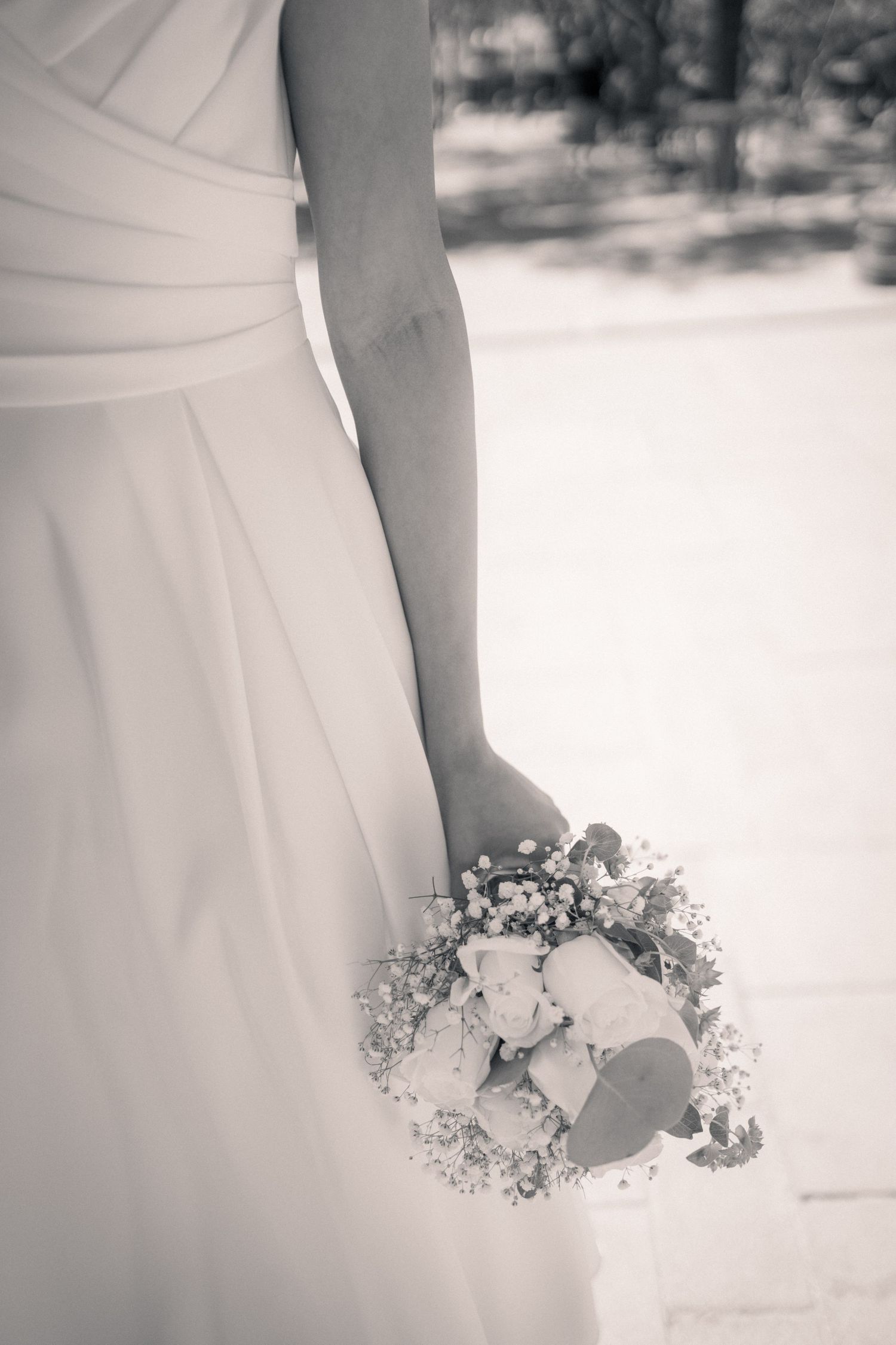 Elegant black and white photo of a bridal bouquet held against a white wedding dress.