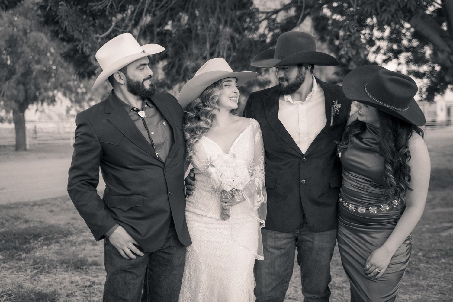Wedding party poses together outdoors in formal attire for black and white portraits.