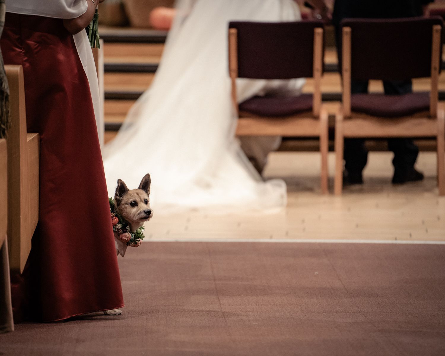 View of a church interior during wedding ceremony with pews and stained glass windows.