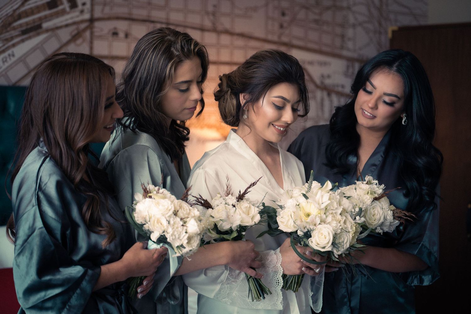 Group wearing matching silk robes holding white floral bouquets in an intimate indoor setting.