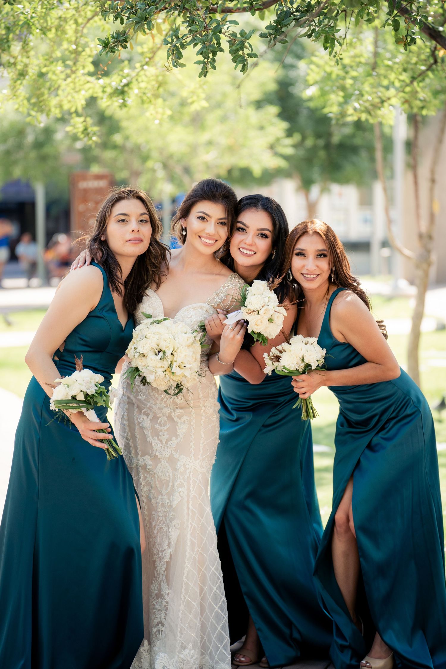 Wedding party photo outdoors with floral bouquets in the sunlight.