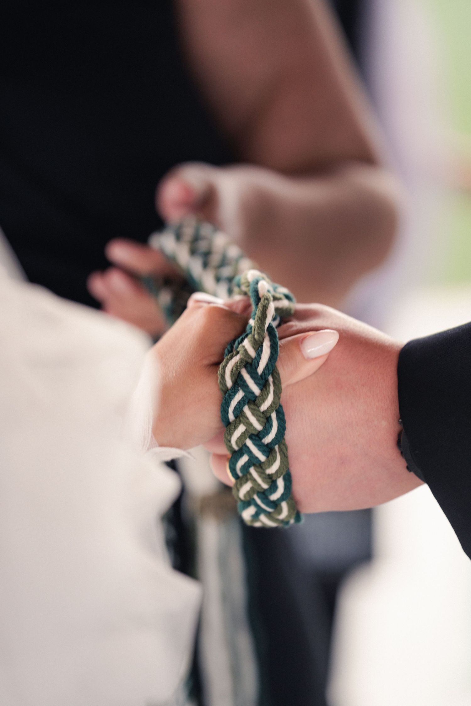 Close-up view of a braided leather bracelet with metallic accents worn on someone's wrist.